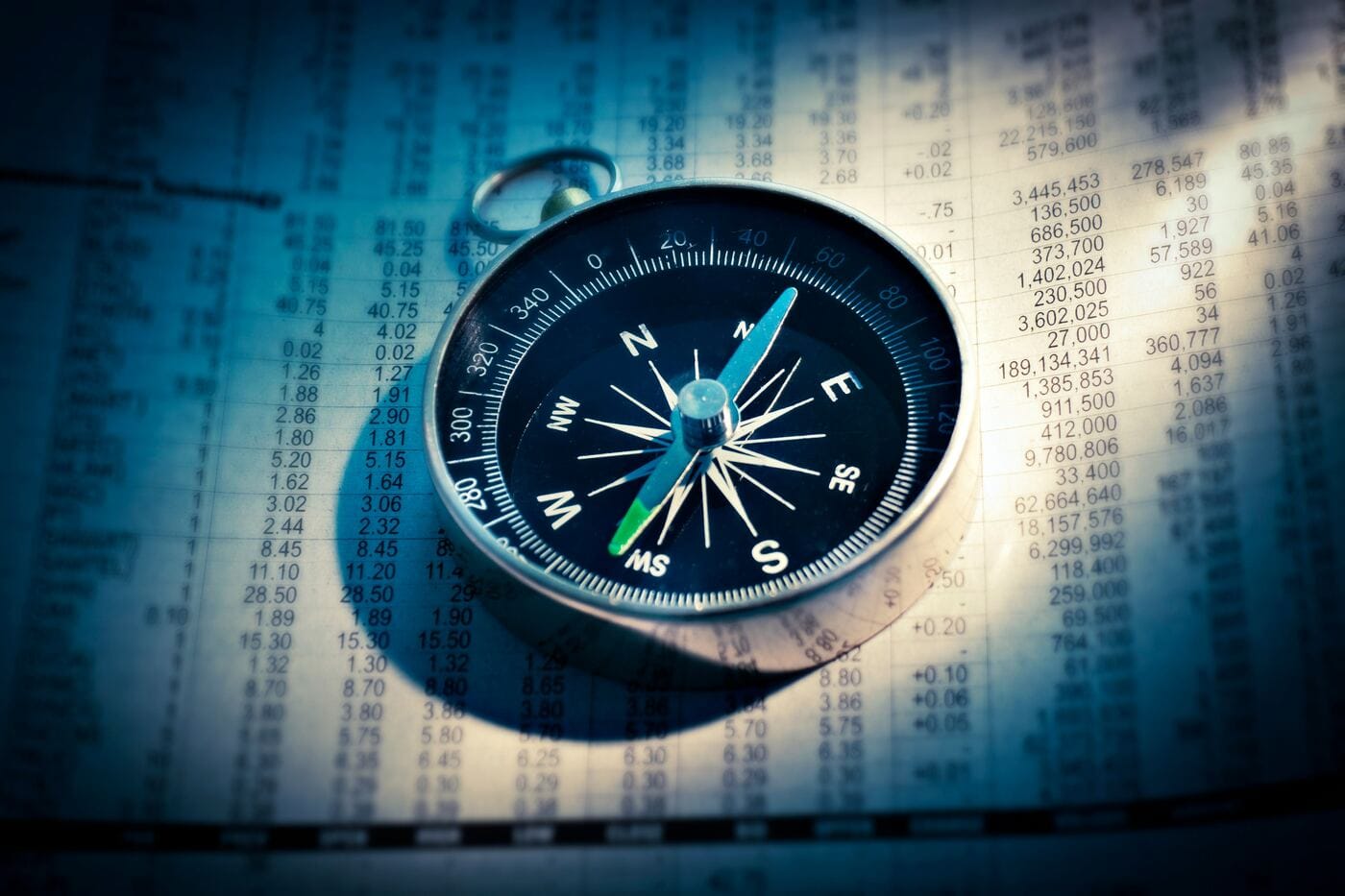 A compass resting on a page of financial figures, representing finding your direction with the calculator below