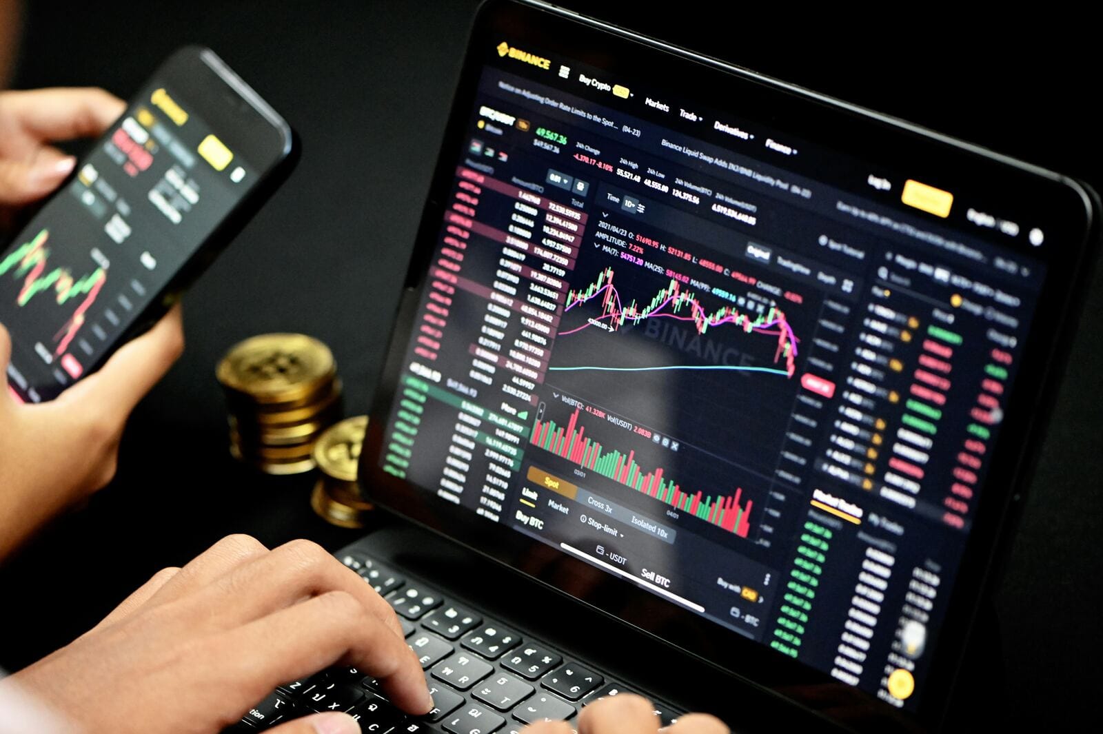 A person tracking live financial charts across a phone and tablet, representing ongoing PAYDEX score monitoring