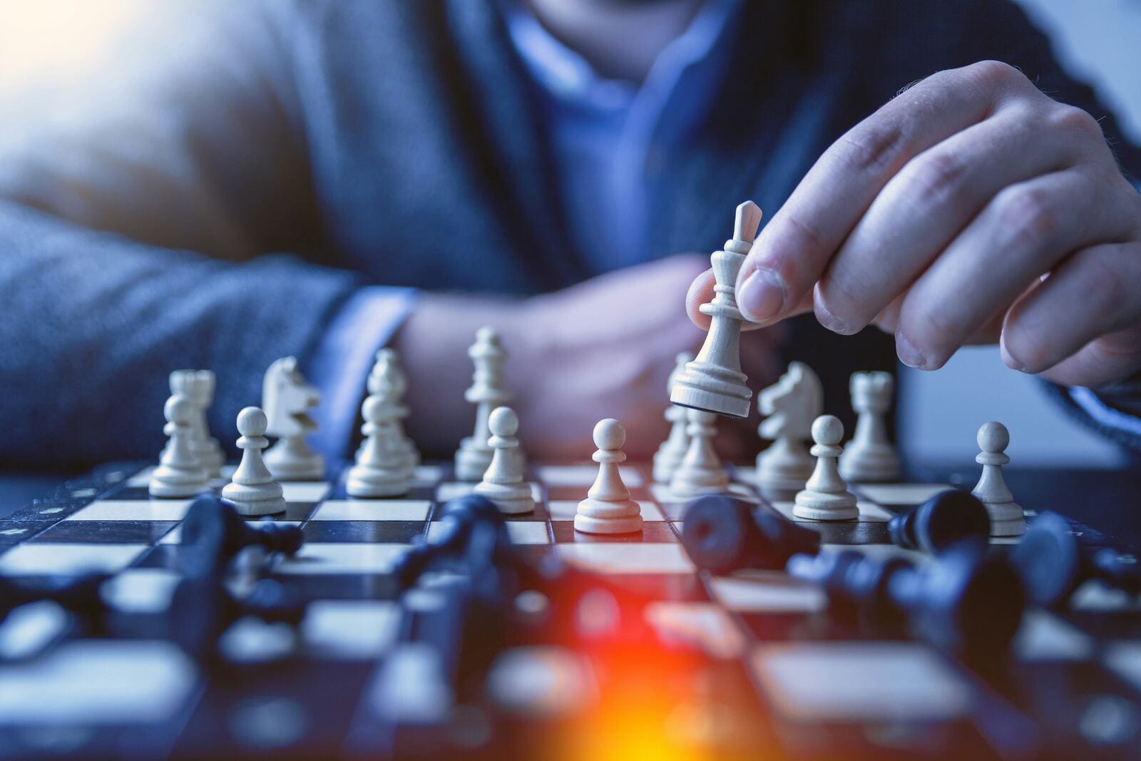 A hand moving a chess piece across a board, representing the strategic decision of choosing a business credit builder