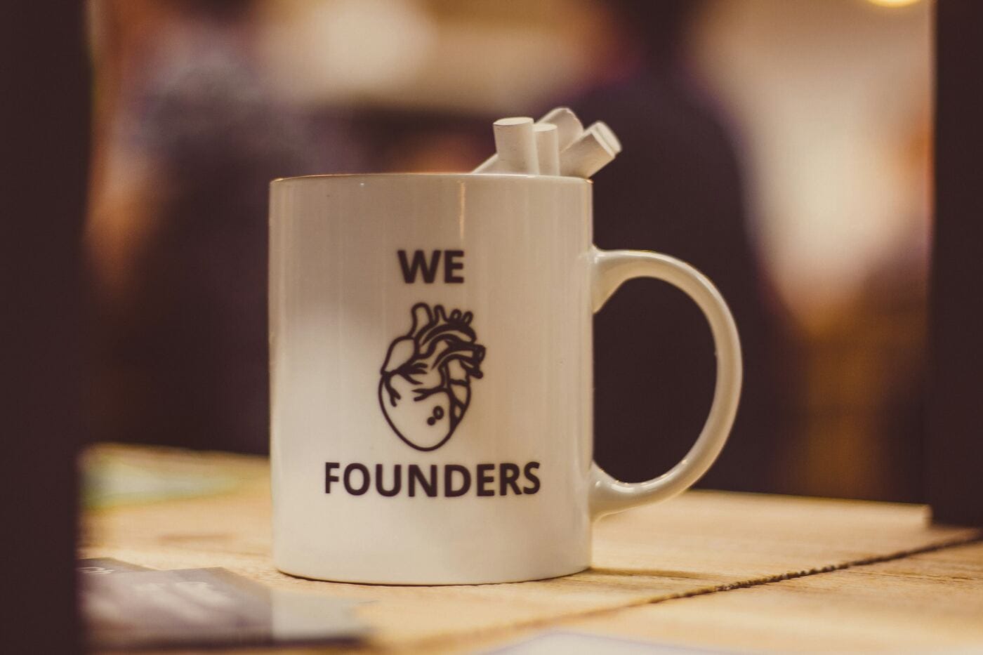 A mug reading 'We [heart] Founders' on a desk, representing who this editorial content is written for